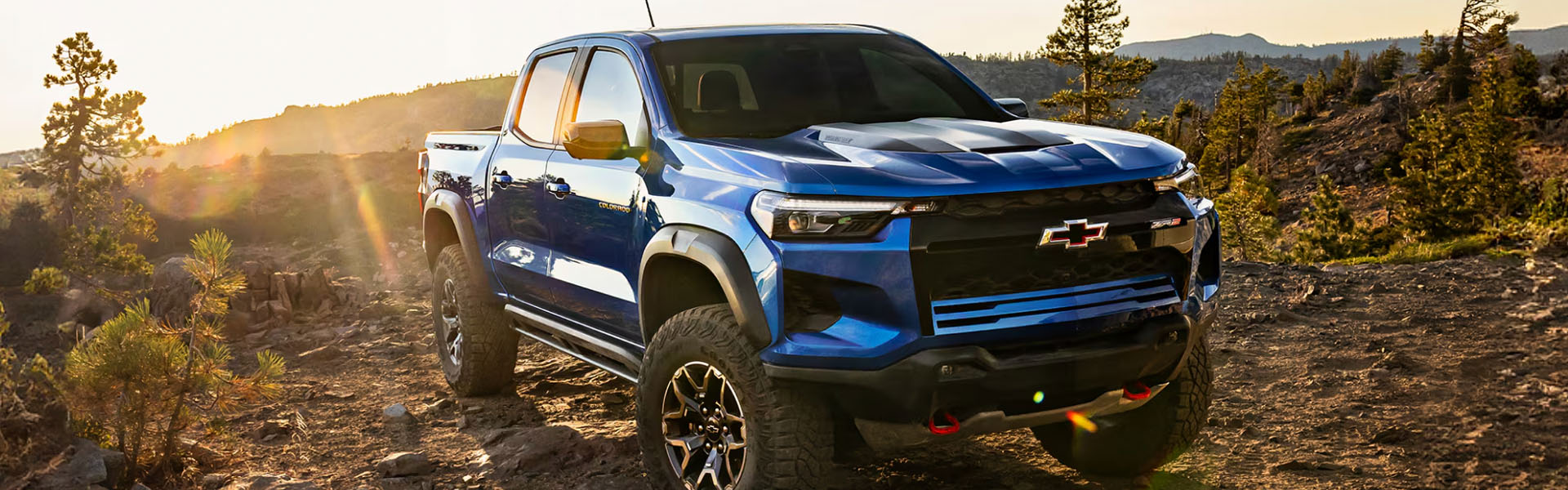 Blue Chevrolet Colorado ZR2 truck on rugged terrain with sunlight.